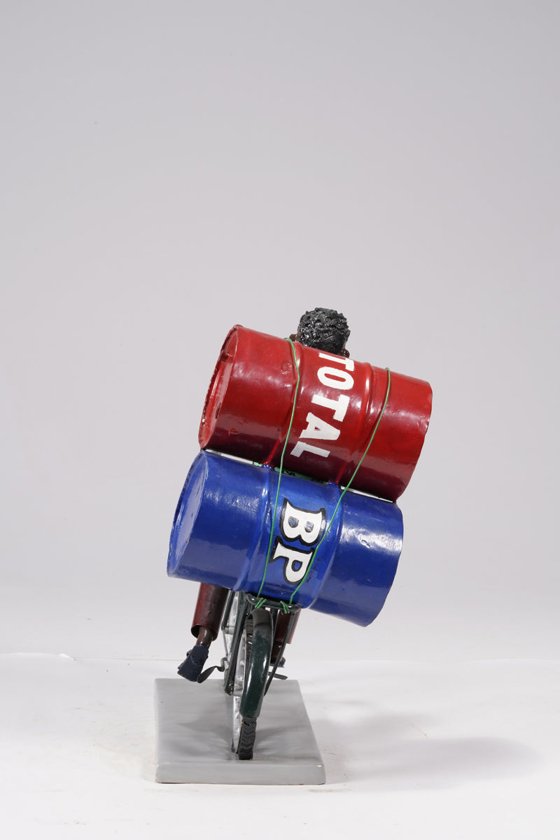 A young man on a bike trasporting petroleum barrels