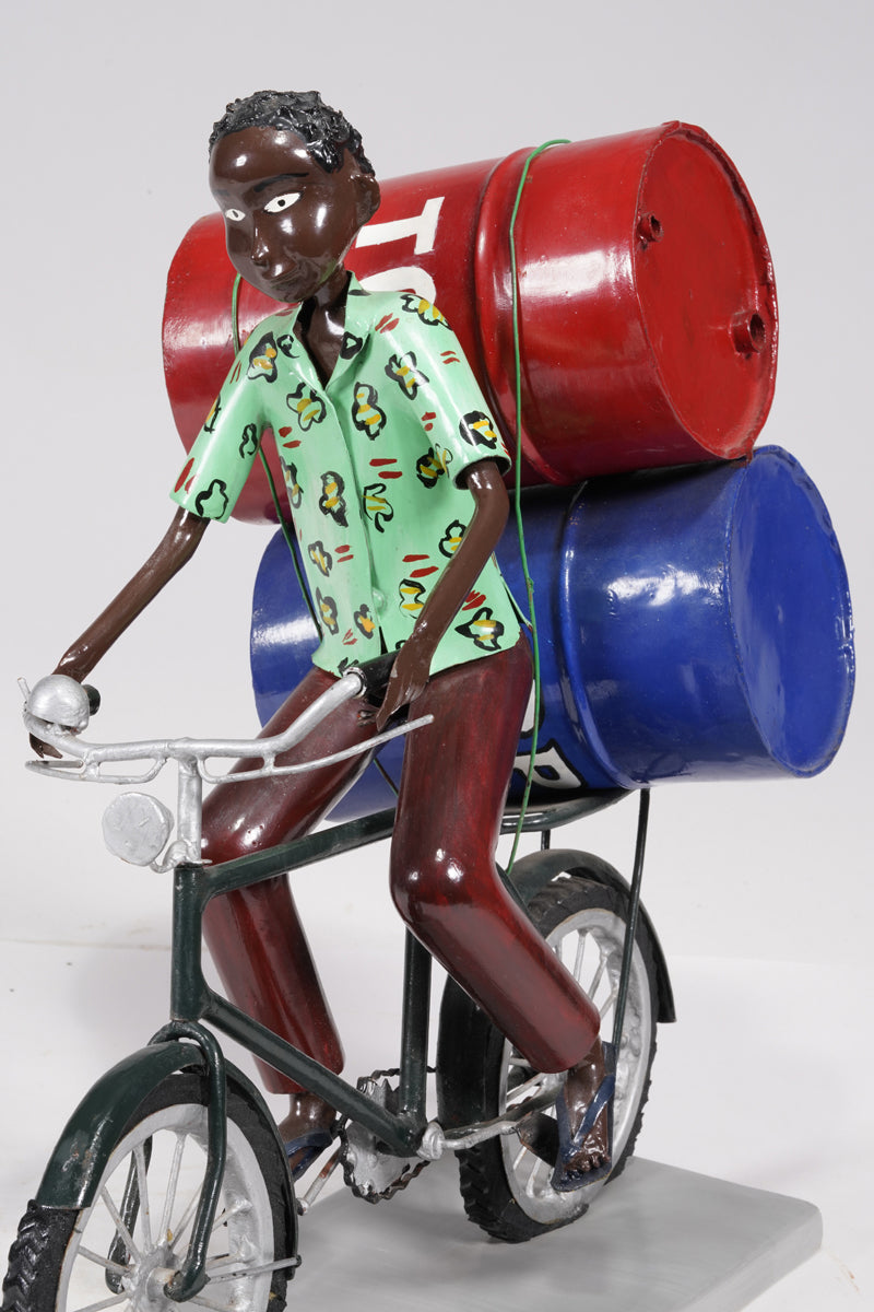 A young man on a bike trasporting petroleum barrels