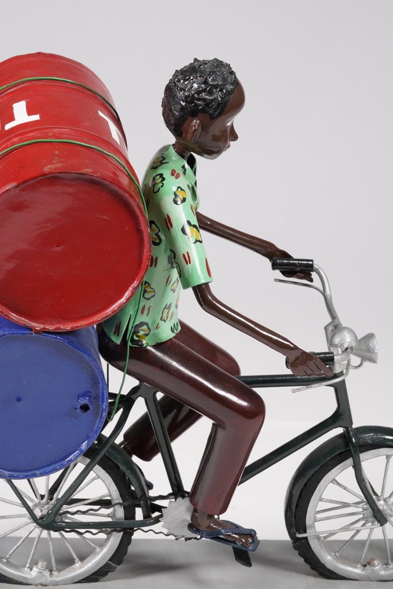 A young man on a bike trasporting petroleum barrels