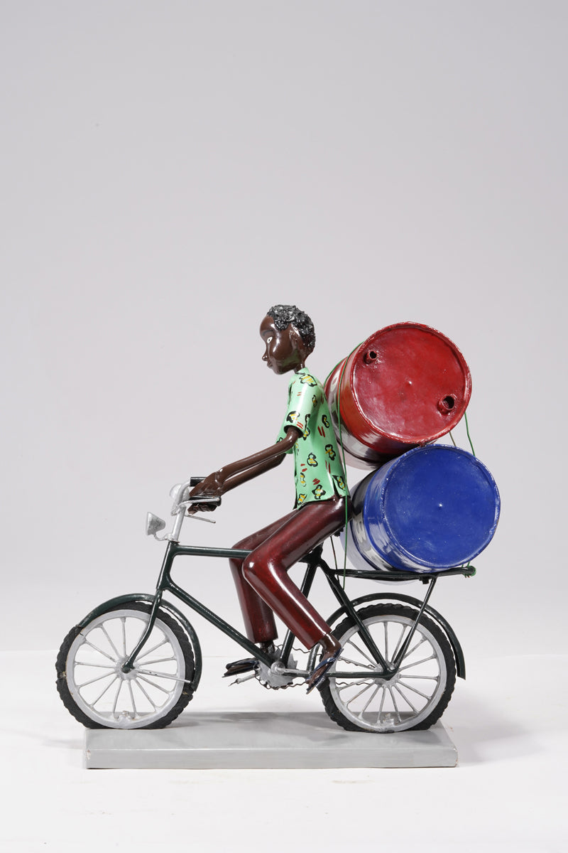 A young man on a bike trasporting petroleum barrels