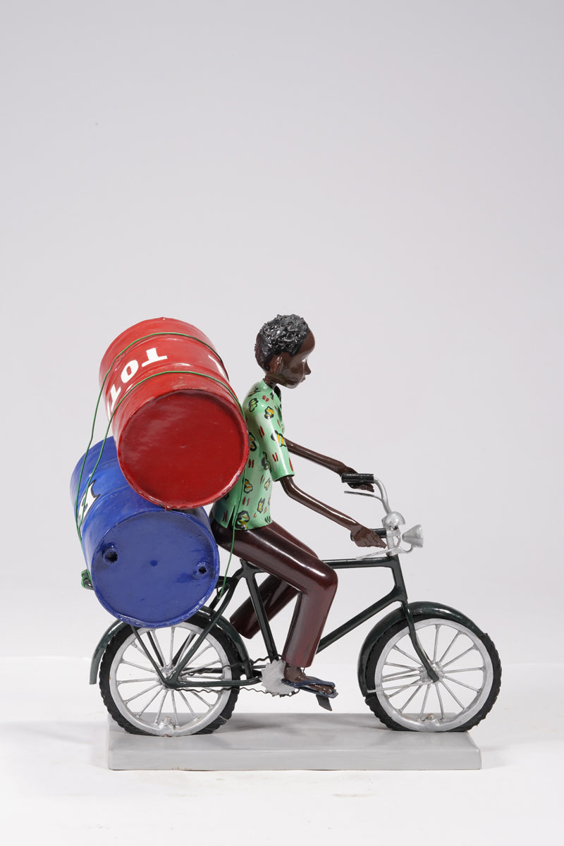 A young man on a bike trasporting petroleum barrels