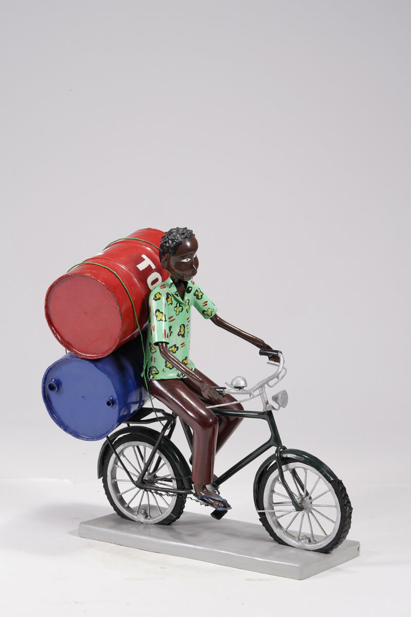 A young man on a bike trasporting petroleum barrels