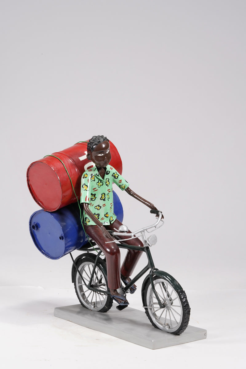 A young man on a bike trasporting petroleum barrels