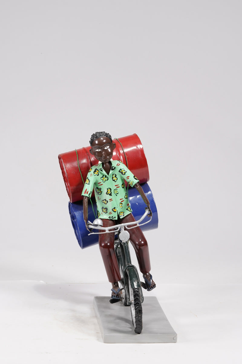 A young man on a bike trasporting petroleum barrels