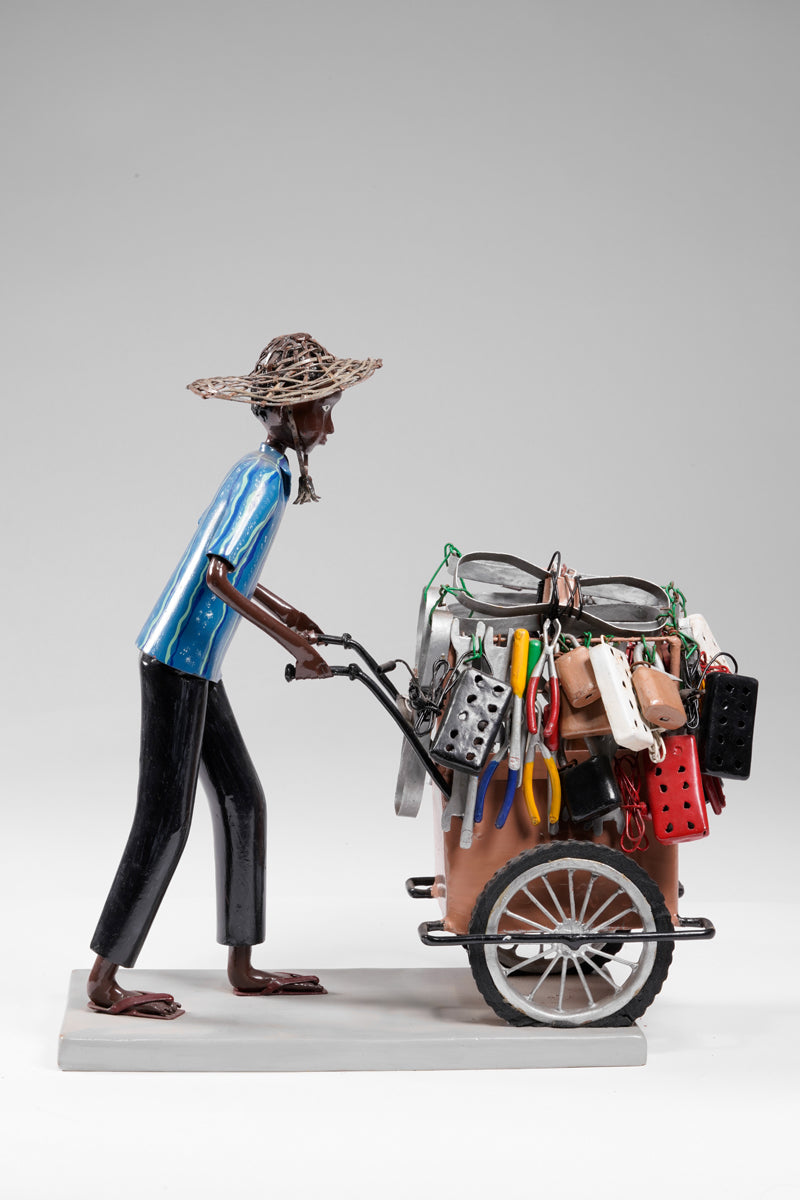 A salesman pushing his goods from the area of a hardware store on a cart